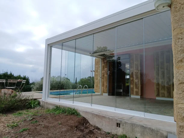 Pergola bioclimatique à lames orientables avec stores intégrés et parois vitrées à Nîmes vue extérieure latérale